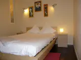 Standard Double room with queen bed, floral paintings above the headboard and a lit bedside lamp